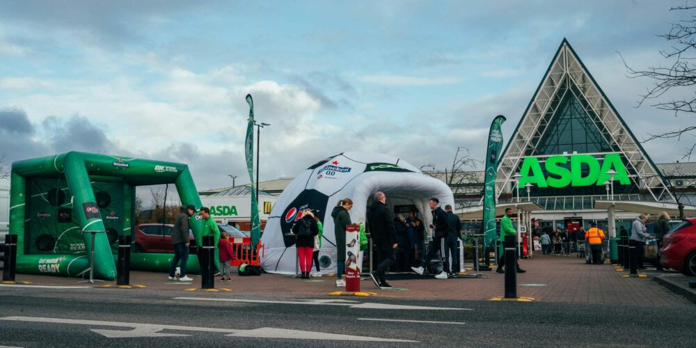 Shoppers gathered at football themed inflatable dome and goalpost out side of an Asda supermarket